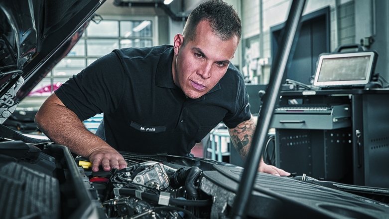 Técnico especializado en taller Mercedes-Benz revisando un motor de un vehículo.
