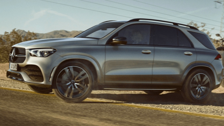 Vista lateral de SUV Mercedes-Benz GLE siendo conducida por terreno rocoso con carga.