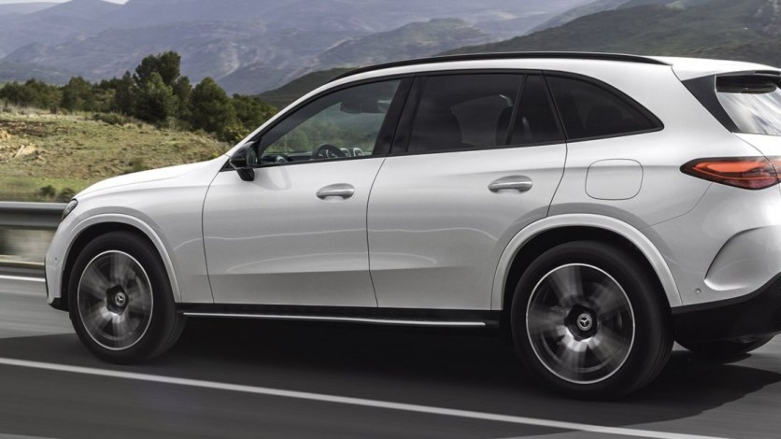 Auto híbrido Mercedes-Benz GLC 200 color blanco siendo conducido por carretera con fondo de montañas.